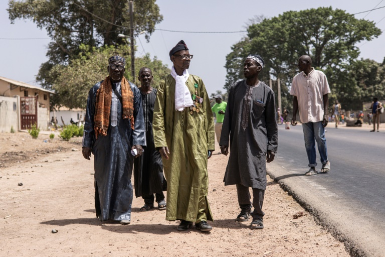 Oumar Diemé (c.), 91 ans, un ancien tirailleur sénégalais marche sur la route à Badiana (Sénégal), le 14 mai 2024