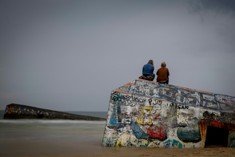 Des gens admirent l'océan depuis les restes d'un bunker du mur de l'Atlantique le 19 mai 2024 près du Cap Ferret (sud-ouest de la France)