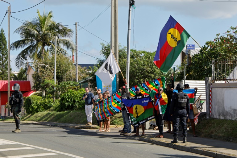 Des manifestants avec des drapeaux kanak sur le parcours du cortège du président de la République Emmanuel Macron à Nouméa, en Nouvelle-Calédonie, le 23 mai 2024
