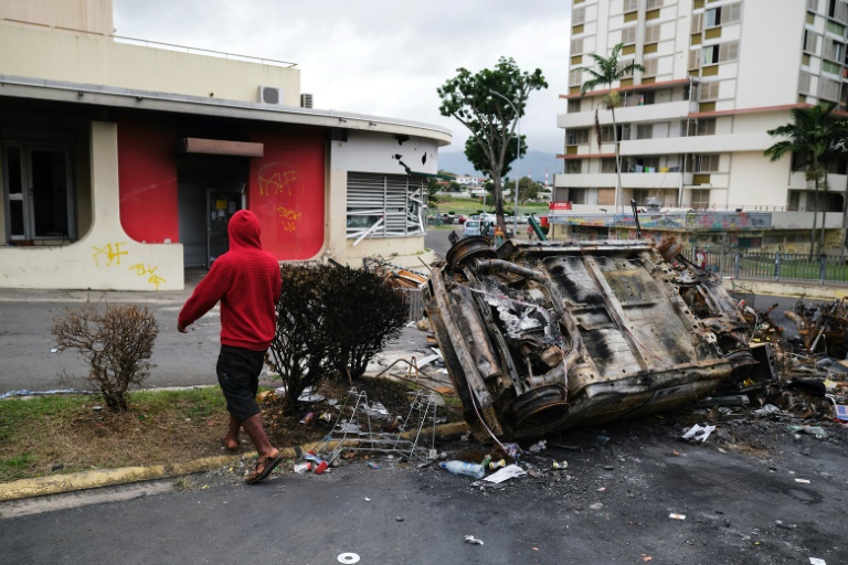 Un homme passe devant un véhicule brûlé lors d'un barrage routier indépendantiste dans le quartier de Magenta à Nouméa, en Nouvelle-Calédonie, territoire français du Pacifique, le 22 mai 2024