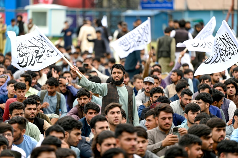 Quelques supporters afghans brandissent le drapeau taliban alors qu'ils suivent sur écran géant à Kaboul le match de leur équipe de cricket contre l'Afrique du Sud, le 27 juin 2024