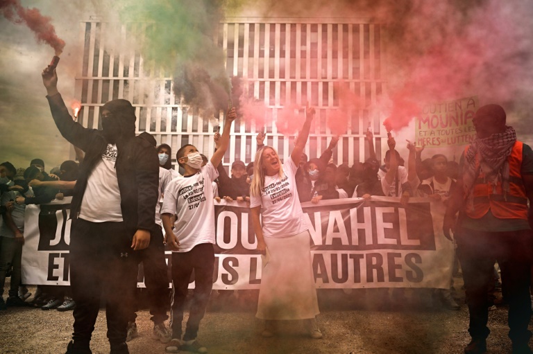 Mounia (c), la mère de Nahel, dans la fumée des fumigènes lors d'une marche en hommage à son fils, un an après sa mort, le 29 juin 2024 à Nanterre, dans les Hauts-de-Seine