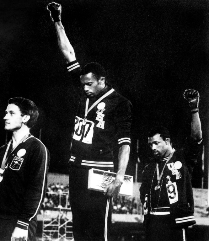 Les Américains Tommie Smith (au centre) et John Carlos (à droite) lèvent un poing ganté de noir sur le podium du 200 m des JO de Mexico, pour protester contre la ségrégation raciale aux Etats-Unis.