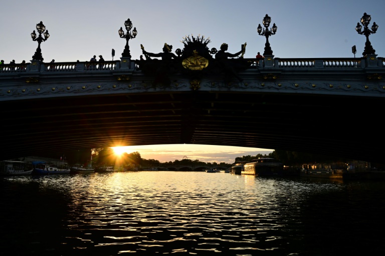 Le soleil apparaît sous le pont Alexandre III au-dessus de la Seine, le 20 août 2023 à Paris