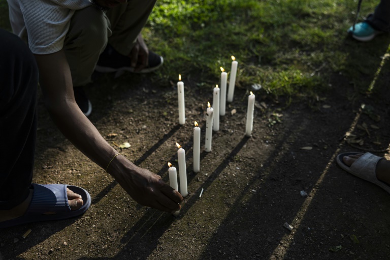 Des migrants allument des bougies en hommage aux personnes mortes lors d'une tentative de traversée de la Manche, le 19 juillet 2024 à Calais