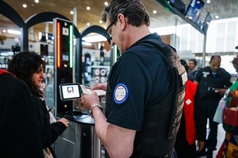 Un policier aide des passagers à passer le contrôle par reconnaissance faciale, le 3 juillet 2024 à l'aéroport de Roissy-Charles de Gaulle