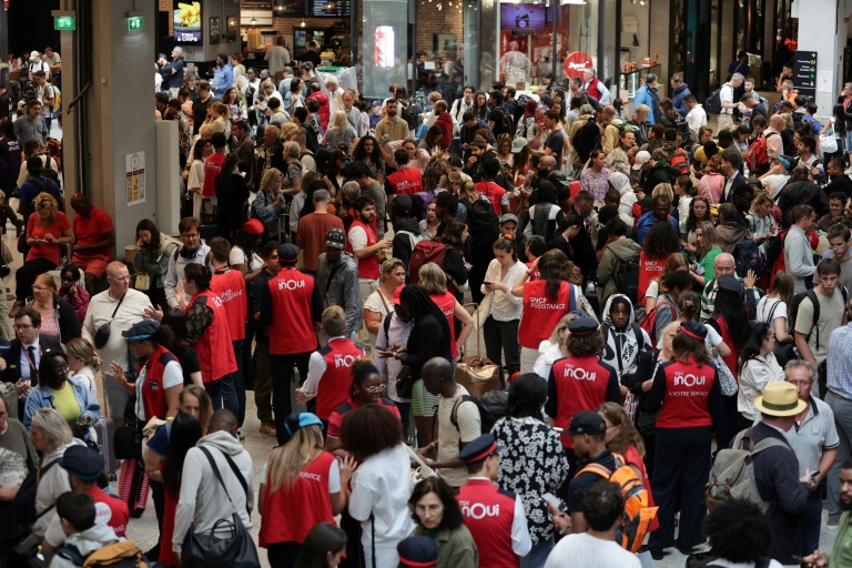 Des agents de la SNCF informent des passagers en attente de leur train à la gare Montparnasse, le 26 juillet 2024 à Paris