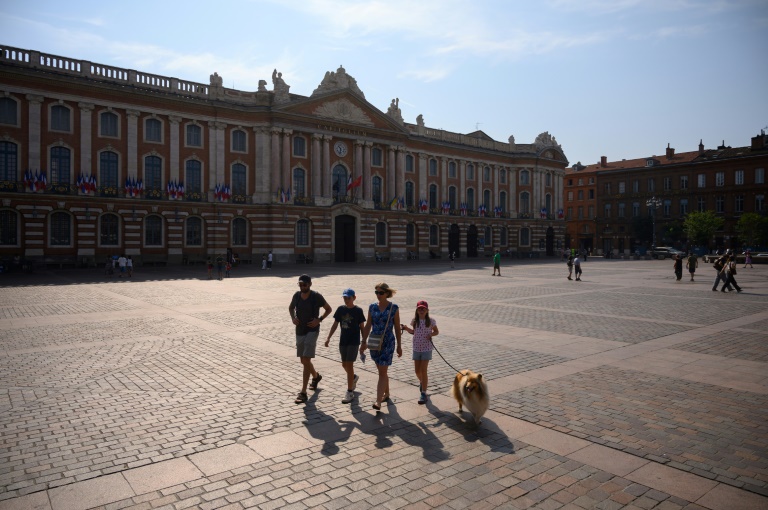 Une famille traverse la Place du Capitole à Toulouse sous le soleil, dans le sud-ouest de la France le 28 juillet 2024