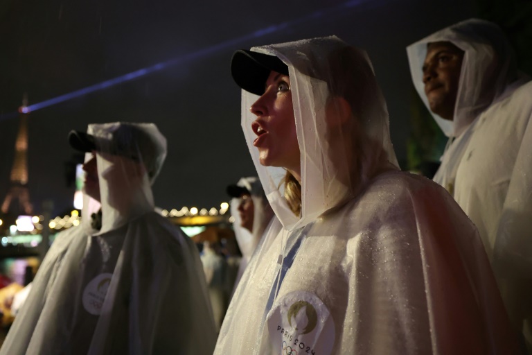 Des spectateurs se protègent de la pluie lors de la cérémonie d'ouverture des JO à Paris le 26 juillet 2026