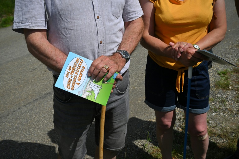 Des promeneurs tiennent à la main un livret expliquant comment se comporter face un chien de protection des troupeaux près de Saint-Etienne-les-Orgues, dans les Alpes-de-Haute-Provence, le 27 juin 2024