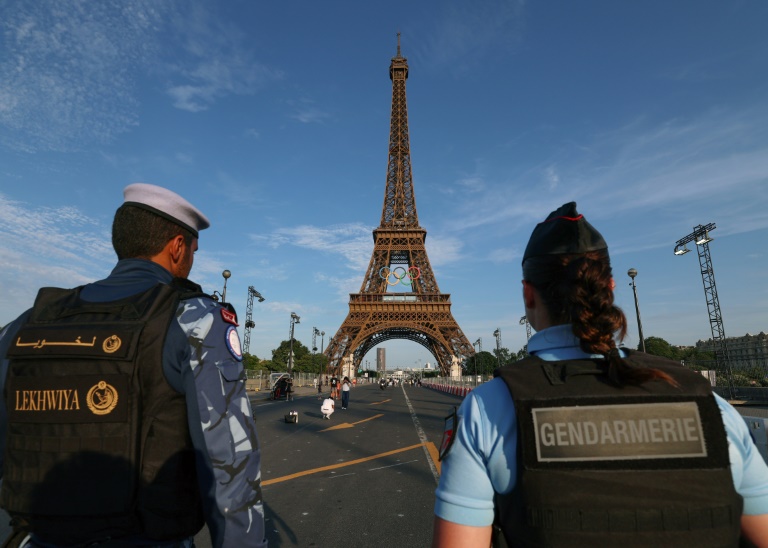 Un membre d'une force de sécurité qatarie (gauche) et une gendarme française se tiennent près de la tour Eiffel, le 18 juillet 2024 à Paris