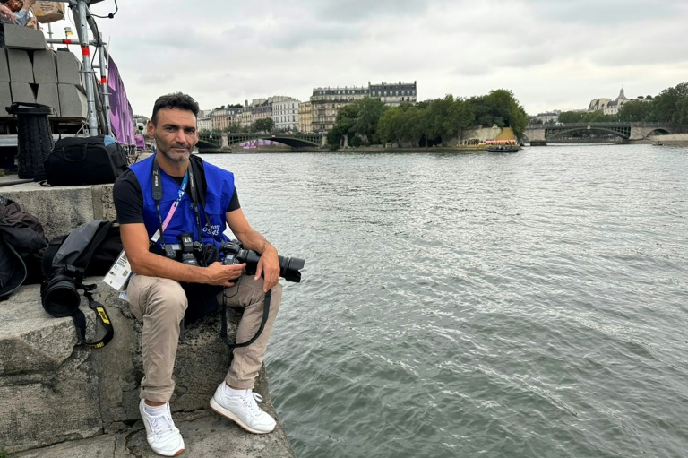 Le photographe de l'Agence France-Presse Aris Messinis au bord de la Seine avant la cérémonie d'ouverture des JO, le 26 juillet 2024 à Paris