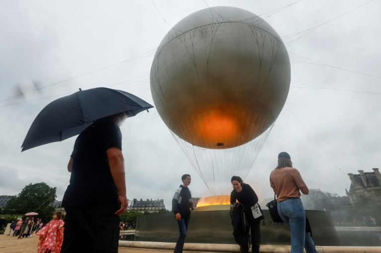 Des visiteurs devant la vasque olympique aux allures de montgolfière posée dans le jardin des Tuileries, le 27 juillet 2024 à Paris