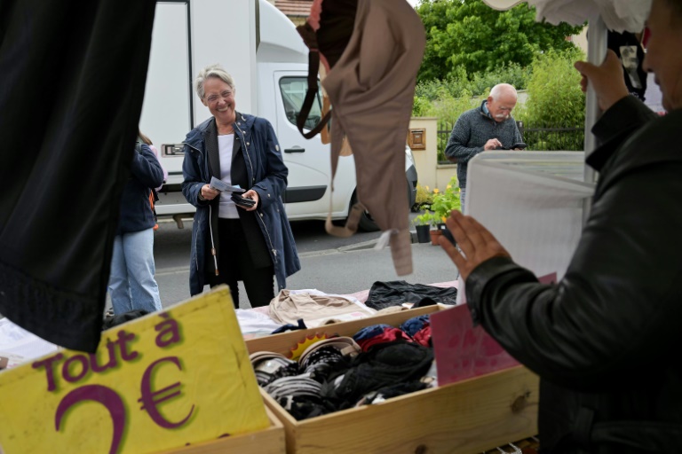L'ancienne Première ministre Elisabeth Borne (c), candidate de la coalition de droite Ensemble aux législatives, distribue des tracts sur un marché à Villers-Bocage, le 3 juillet 2024 dans le Calvados