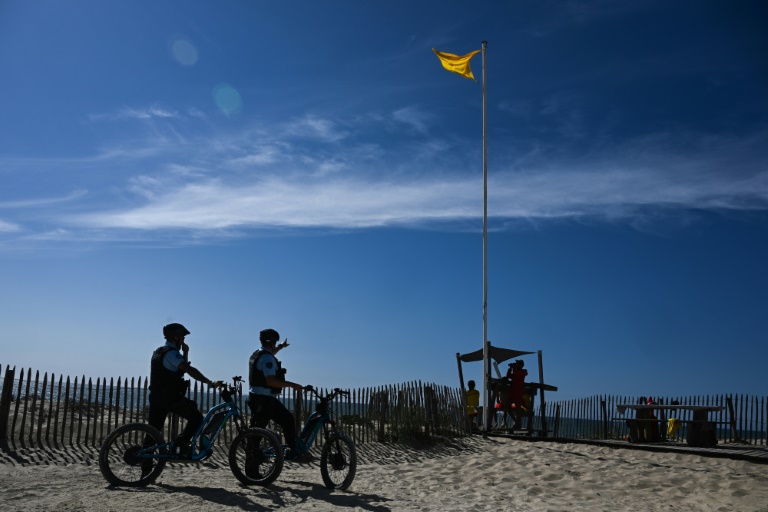 Des gendarmes, en scooters électriques tout-terrain, patrouillent le long d'une plage de pins à Lacanau, le 8 août 2024 en Gironde