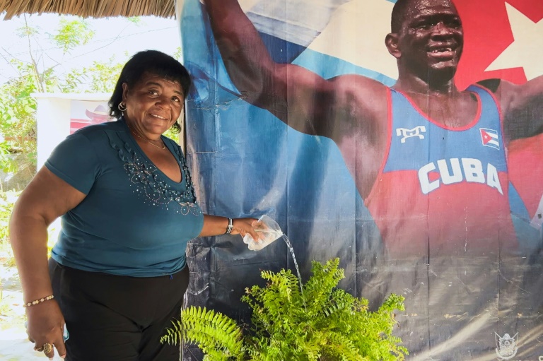 Leonor Nunez, mère du lutteur cubain Mijain Lopez, devant une affiche de son fils dans la ville natale du champion olympique, à Herradura, à Cuba, le 19 juillet 2024