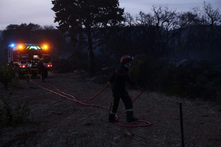 Un pompier déploie un tuyau  près d'un incendie à Frontignan, dans l'Hérault, le 18 août 2024