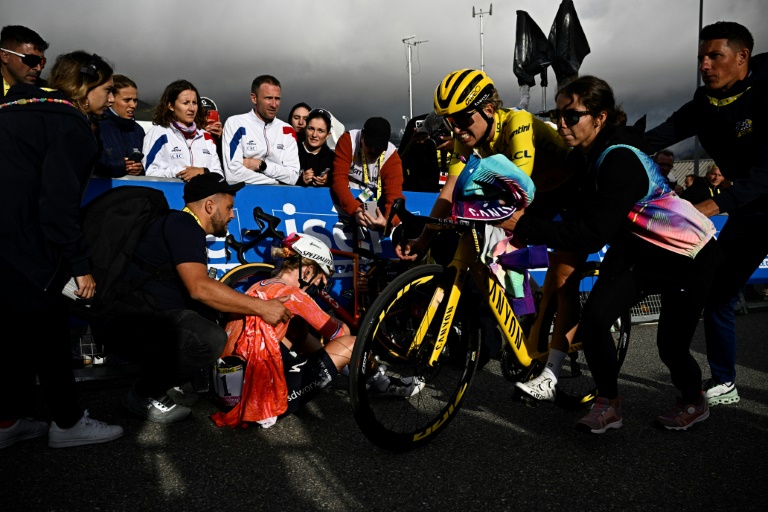 La Polonaise Katarzyna Niewiadoma (en jaune) passe la ligne d'arrivée de la dernière étape du Tour de France, alors que la Néerlandaise Demi Vollering (en orange) est assise par terre, à l'Alpe d'Huez, en France, le 18 août 2024