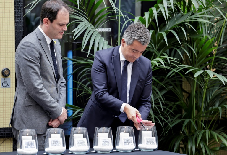 Le ministre de l'Intérieur Gérald Darmanin (à droite), allume une bougie portant le nom d'une victime de l'attentat de la rue des Rosiers à Paris, le 9 août 1982, en compagnie du président du Conseil représentatif des institutions juives de France (Crif) Yonathan Arfi, sur les lieux de l'attaque contre un restaurant juif lors d'une cérémonie marquant son 42e anniversaire vendredi