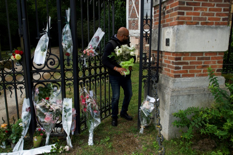 Un homme tient des fleurs devant une entrée de la propriété d'Alain Delon, à Douchy (Loiret), le 18 août 2024