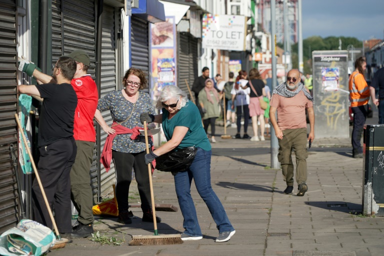 Des habitants nettoient les rues de Middlesbrough, dans le nord-est de l'Angleterre, le 5 août 2024, après des émeutes et des pillages la veille