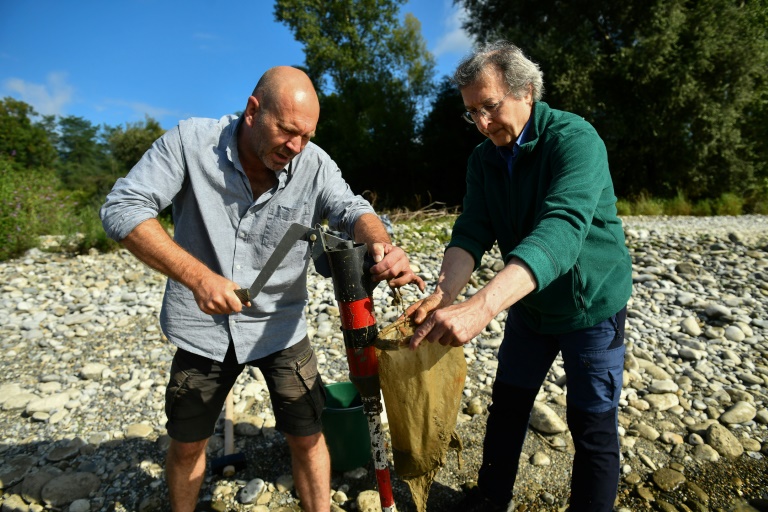 Le biologiste François Lefebvre (gauche) et l'hydrogéologue Thierry Alezine cherchent des niphargus, des micro-crustacés, sur les rives du Gave de Pau à Artiguelouve, dans le sud-ouest de la France, le 21 août 2024