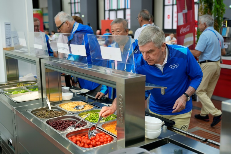 Le président du Comité international olympique (CIO), Thomas Bach, se sert au bar à salades du restaurant du village olympique, à Saint-Denis près de Paris, le 22 juillet 2024, avant l'ouverture des JO.