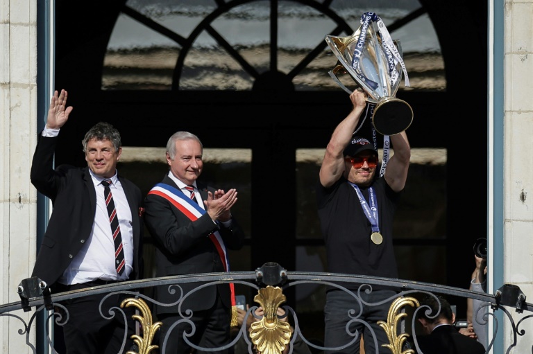 Le président du Stade toulousain Didier Lacroix, le maire de Toulouse Jean-Luc Moudenc et Antoine Dupont (de gauche à droite) célèbrent la victoire en Champions Cup sur la place du Capitole le 26 mai 2024