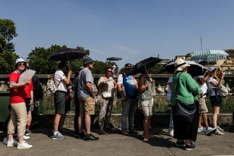 Des promeneurs se protègent du soleil, le 30 juillet 2024 à Paris