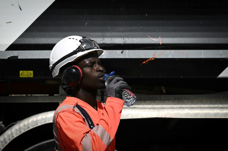 Un ouvrier travaillant sur la maintenance des voies de tramway à Bordeaux s'hydrate en pleine vague de chaleur, le 29 juillet 2024