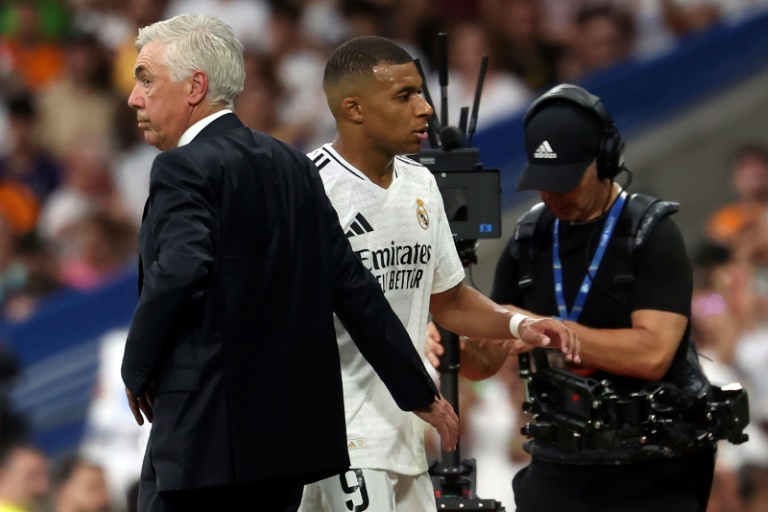 L'attaquant français du Real Madrid Kylian Mbappé salue l'entraîneur Carlo Ancelotti au moment de sa sortie lors de la victoire contre Valladolid au stade Santiago Bernabeu de Madrid le 25 août 2024