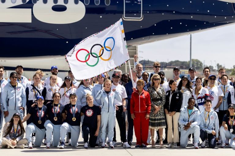 La maire de Los Angeles Karen Bass pose avec le drapeau olympique et plusieurs athlètes américains à son retour dans la ville, le 12 août 2024