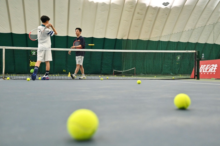 Zhang Xinghao (g) et son entraîneur Nie Baochao pratique le tennis à l'Académie internationale de tennis de Pékin, le 13 août 2024