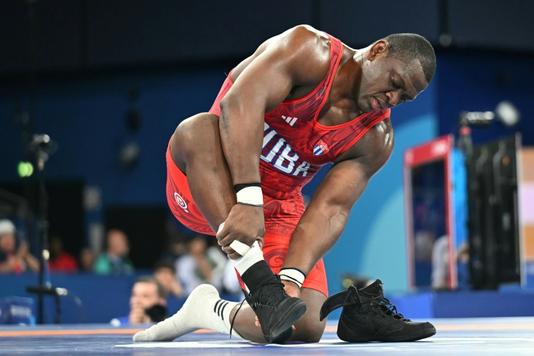 Le lutteur cubain Mijain Lopez enlève ses chaussures après son 5e titre olympique, lors des JO de Paris le 6 août 2024, une tradition pour les lutteurs prenant leur retraite