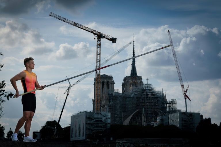 Le perchiste français Thibaut Collet et la cathédrale Notre-Dame de Paris en arrière plan, lors d'une séance photo pour l'AFP, le 3 juin 2024