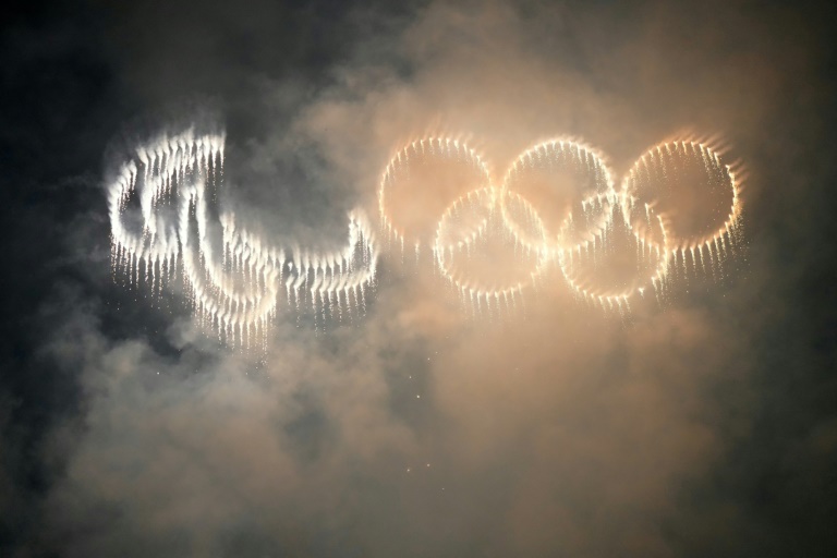 Des lumières illuminent le ciel avec les anneaux des Jeux olympiques et paralympiques devant la tour Eiffel le 14 juillet 2024 à Paris