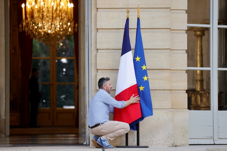 Un homme arrange les drapeaux à l'entrée de l'Hôtel de Matignon, le 30 juin 2024