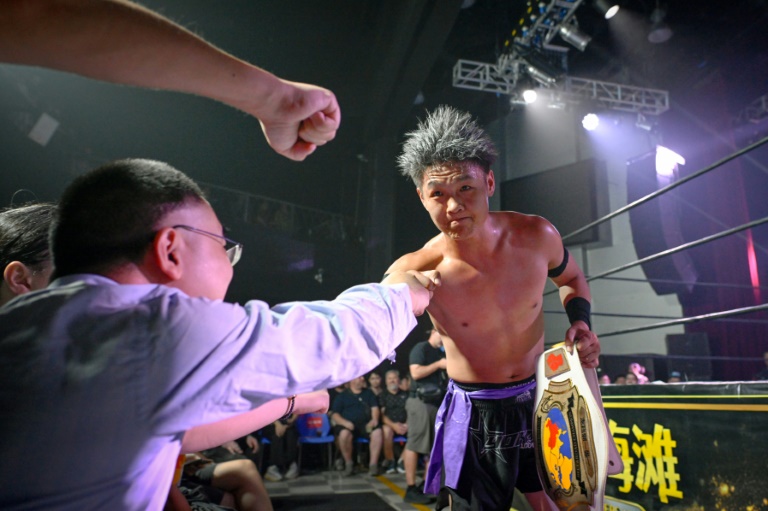 Wang Tao (d) salue ses supporters après avoir remporté le championnat de Middle Kingdom Wrestling (MKW),le 14 septembre 2024 à Shanghai