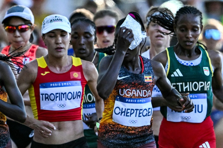 L'Ougandaise Rebecca Cheptegei (c) applique un sac de glace sur sa tête alors qu'elle participe au marathon féminin de l'épreuve d'athlétisme des Jeux olympiques de Paris 2024, le 11 août 2024 à Paris