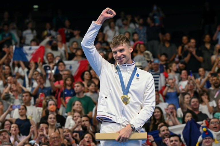 Léon Marchand célèbre sa médaille d'or en 200 m brasse aux Jeux olympiques de Paris, sur le podium de la Défense Arena, à Nanterre le 1er août 2024