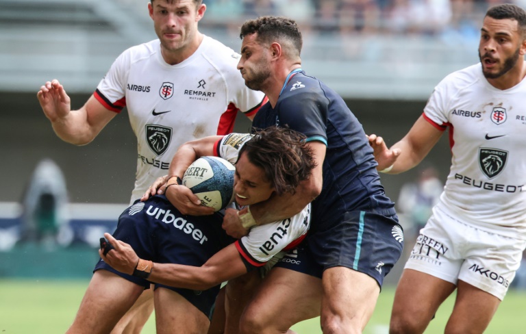 L'Italien du Stade toulousain Ange Capuozzo ballon en main devant le Montpelliérain Thomas Darmon (c), le 21 septembre 2024 à Montpellier