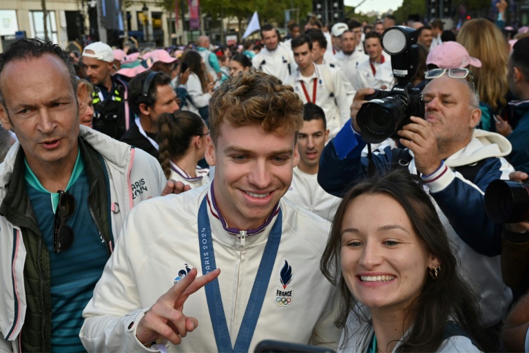 Le nageur Léon Marchand avec des supporters lors du défilé des athlètes français ayant participé aux Jeux olympiques et paralympiques, sur l'avenue des Champs-Élysées à Paris, le 14 septembre 2024