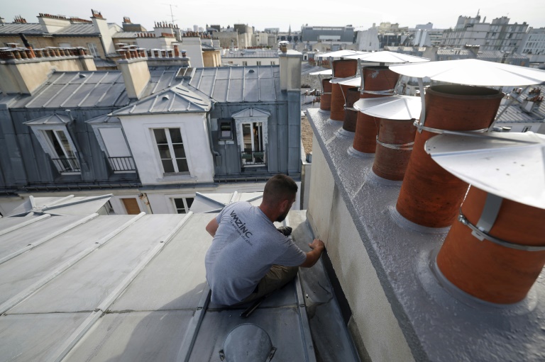 Un couvreur-zingueur répare les solins d'une cheminée pour prévenir les fuites sur le toit d'un immeuble couvert de zinc à Paris, le 31 juillet 2024