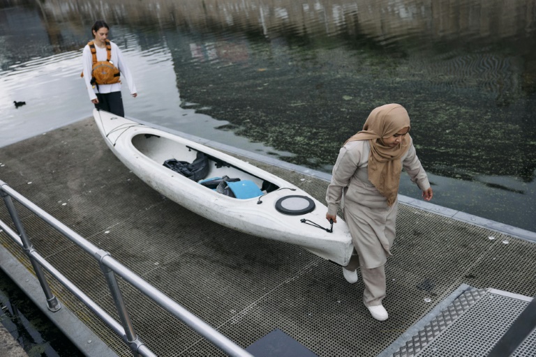 Deux femmes rangent le matériel après un cours de kayak et paddle sur un canal de l'est de Londres en septembre 2024