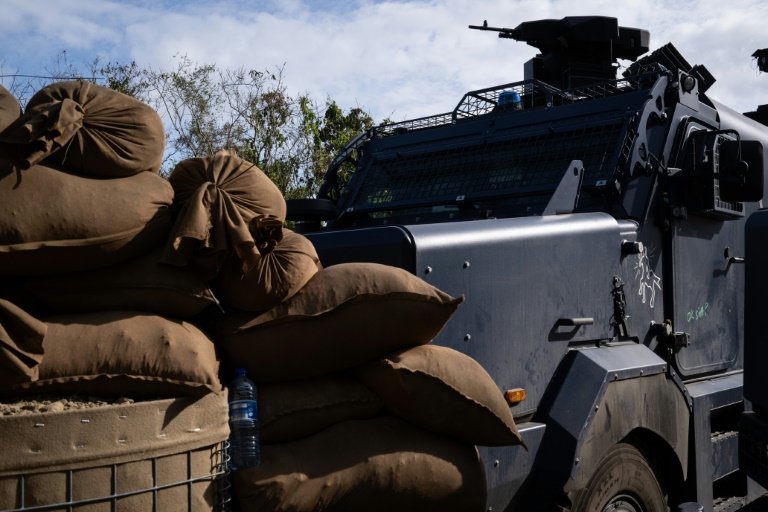 Des sacs de sable marron entassés à côté d'un véhicule blindé de la gendarmerie stationné à un barrage routier à Saint-Louis, au sud de Nouméa, le 23 septembre 2024 en Nouvelle-Calédonie