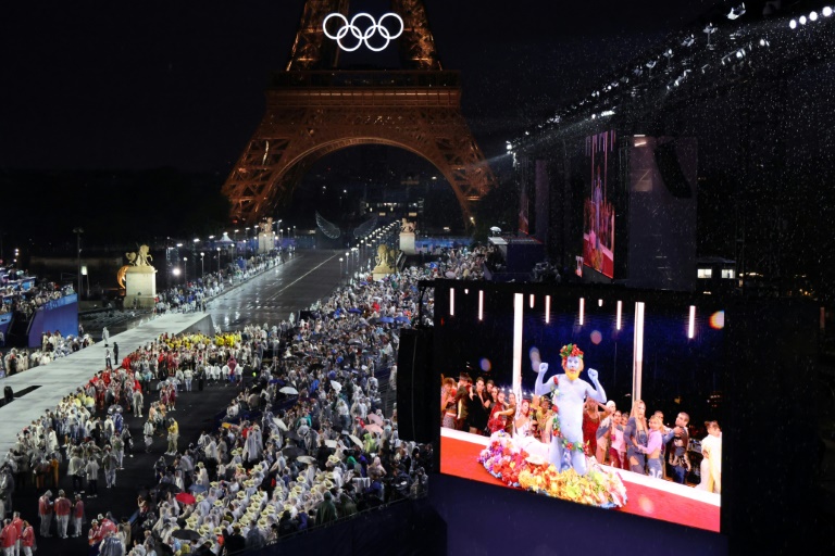 Les délégations d'athlètes arrivent au Trocadéro alors que les spectateurs regardent le chanteur français Philippe Katerine se produire sur un écran géant lors de la cérémonie d'ouverture des Jeux olympiques de Paris 2024, à Paris, le 26 juillet 2024