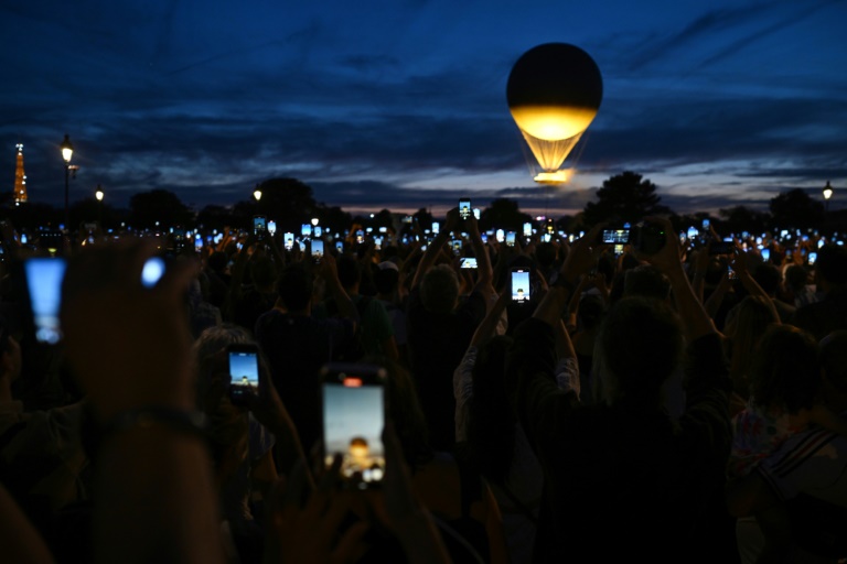 Des visiteurs photographient la vasque olympique accrochée à un ballon, le 6 août 2024 à Paris