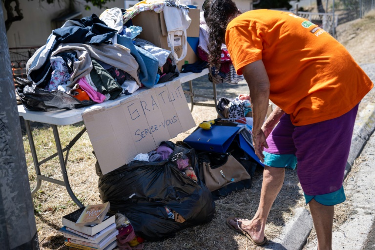 Une habitante regarde des cartons de dons de vêtements sur le bord d'une route du quartier de Rivière Salée à Nouméa, le 26 septembre 2024 en Nouvelle-Calédonie