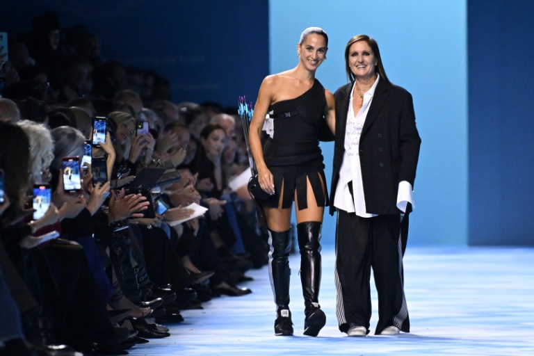 La directrice artistique des lignes féminines, Maria Grazia Chiuri (d) et l'artiste italienne SAGG Napoli saluent le public à l'issue du défilé Dior de la collection prêt-à-porter féminin printemps-été 2025 à la Fashion Week de Paris, le 24 septembre 2024