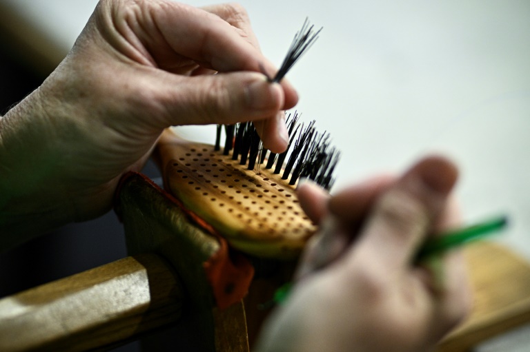 Un employé place à la main les poils d'une brosse à cheveux dans un cadre en bois à l'usine de brosses Altesse à Mouy,dans l'Oise, le 9 octobre 2024